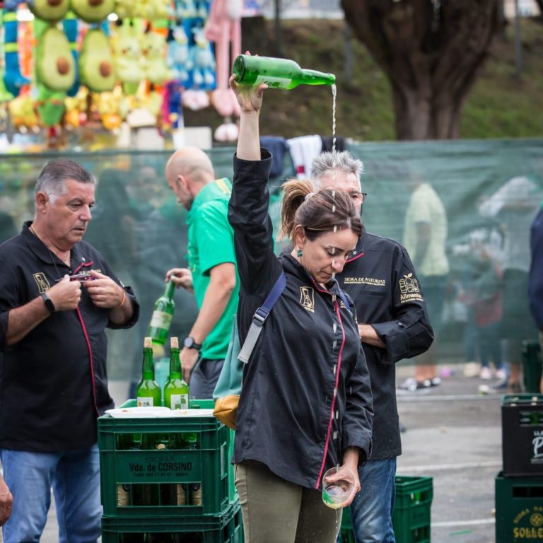 Mujer escanciando una botella de sidra durante el festival
